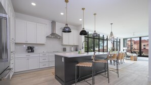 A modern kitchen with white cabinets, a central island, and pendant lighting.