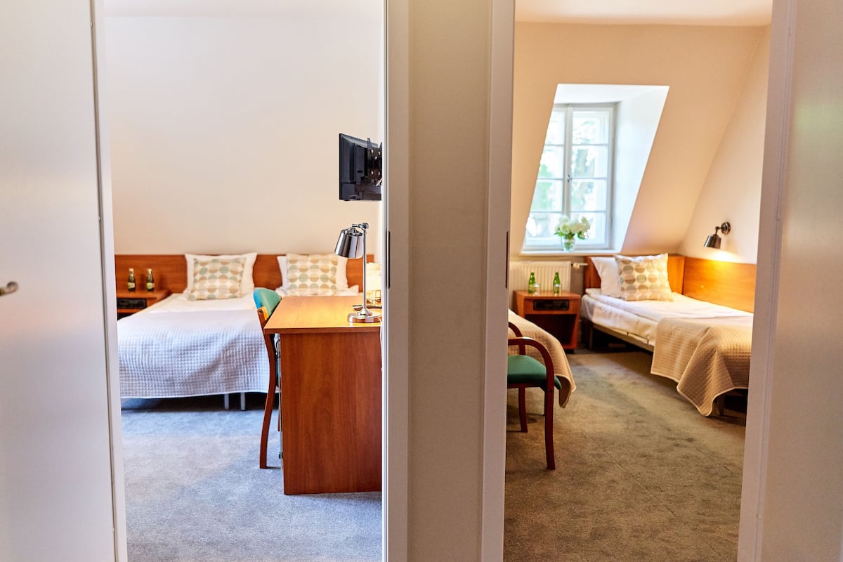 Un dormitorio con cama, escritorio y silla. Hay una ventana con vistas al exterior.