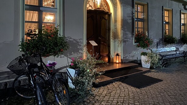 Un edificio con fachada de piedra, una puerta de madera con arco y una bicicleta estacionada afuera.