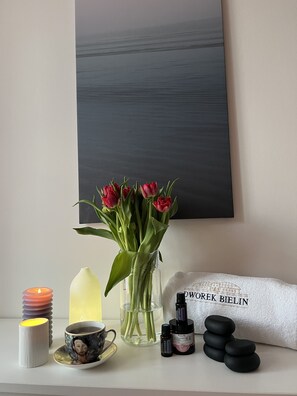 Une pièce décorée d’un vase de tulipes rouges, d’une bougie, d’un diffuseur et d’une serviette sur laquelle est inscrit le texte « DWORER BIELIN ».