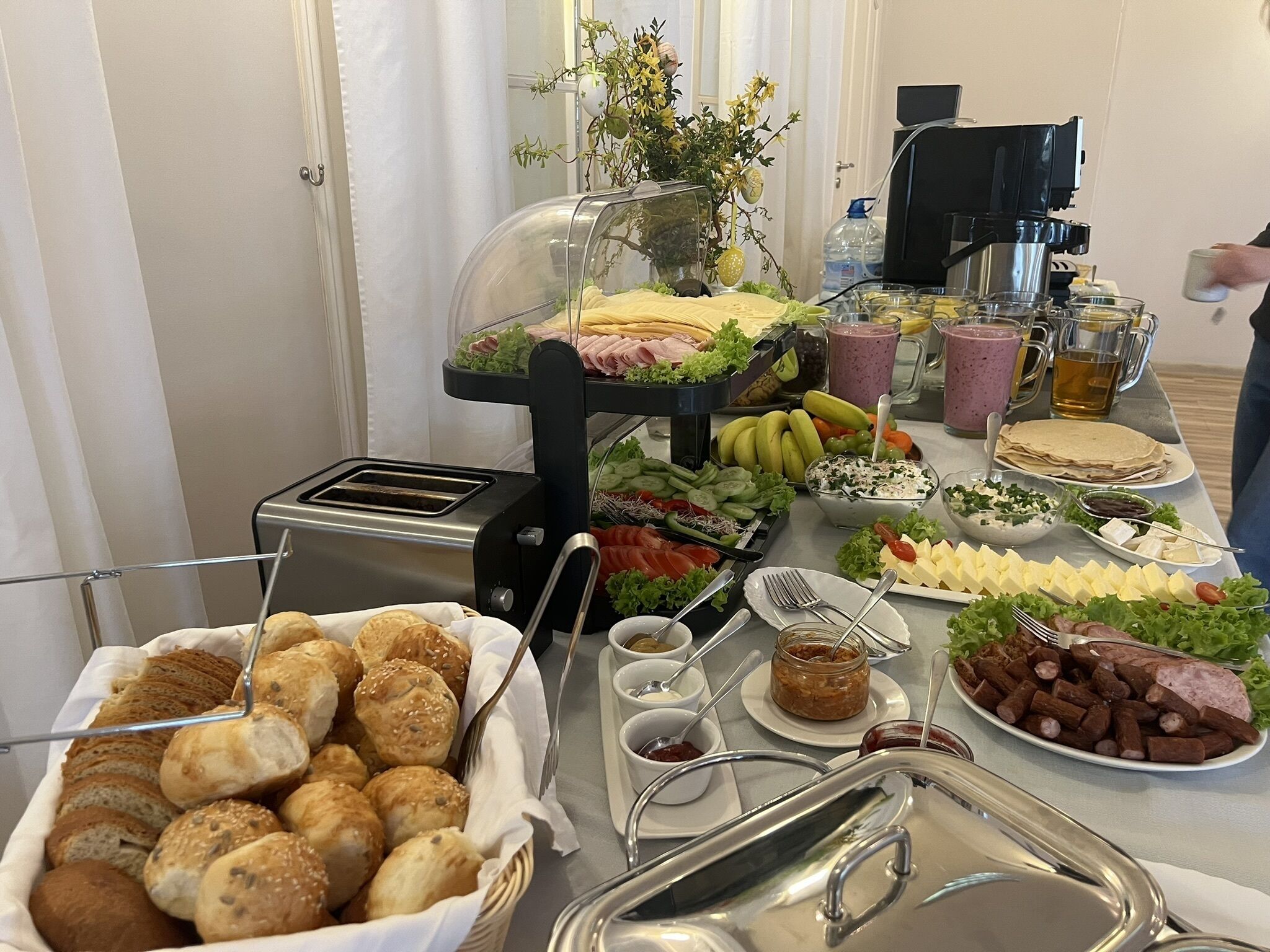 A buffet table with various food items, including bread, cheese, meats, and salads.