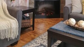 Una sala de estar con chimenea, un sofá, una mesa de centro y un jarrón decorativo.