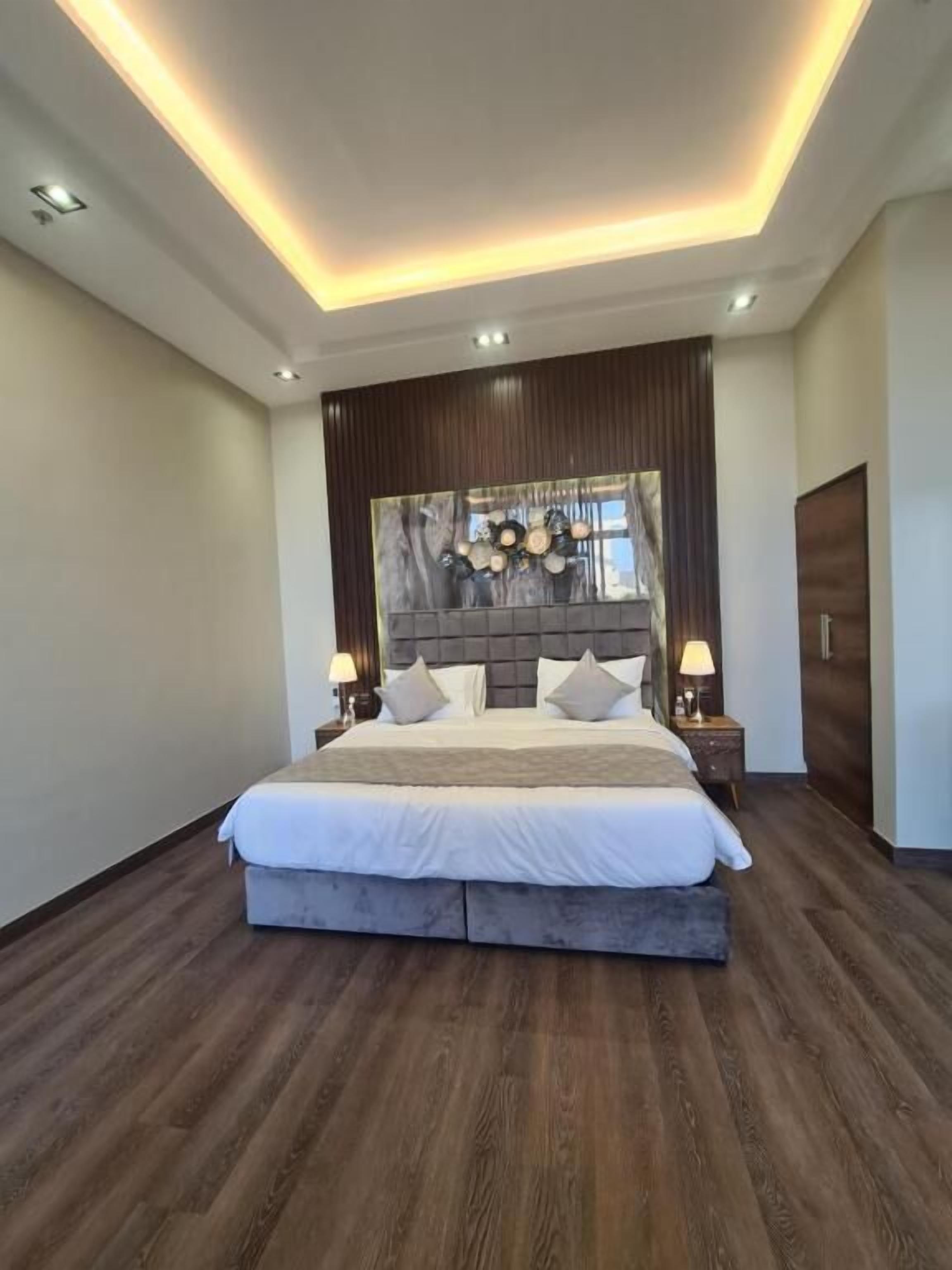 Un dormitorio moderno con una cama grande, suelo de madera e iluminación empotrada en el techo.