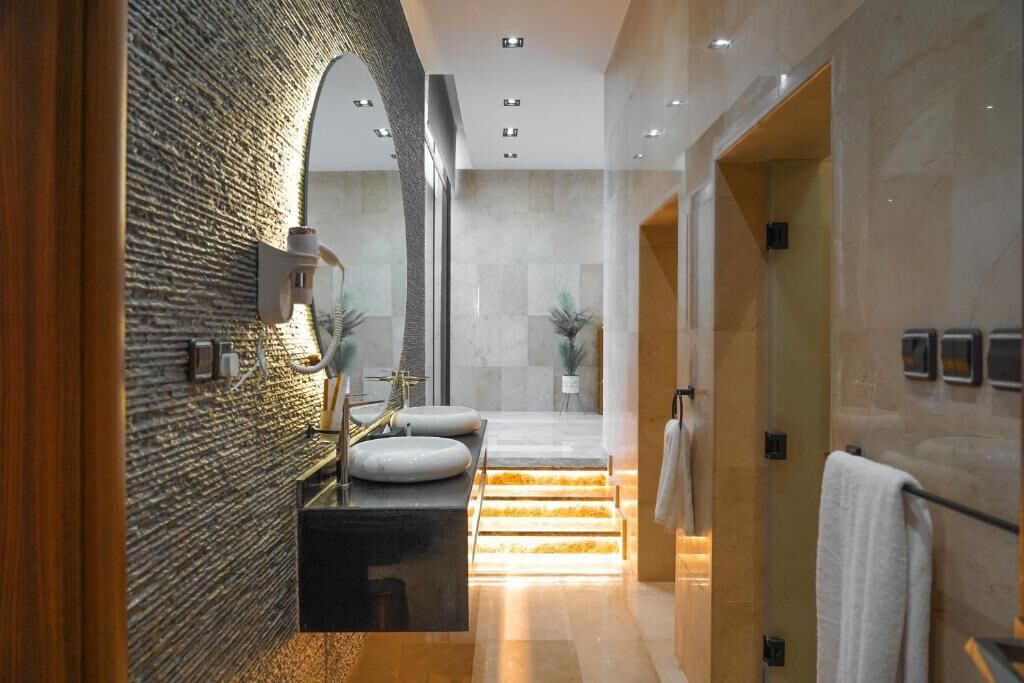 A modern bathroom with a textured wall, a black vanity, a mirror, and a shower area.