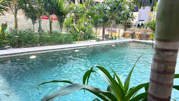 A pool surrounded by lush greenery and a stone wall.