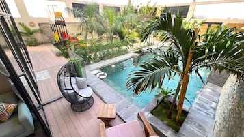 Relax by the pool surrounded by lush greenery and comfortable seating options.