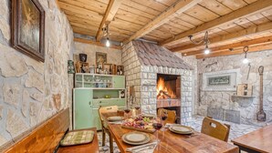 A rustic dining area with a stone fireplace, wooden beams, and a green cabinet. - Coastal Paradise Villa With Pool (Sveti Filip i Jakov)