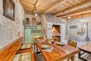A rustic dining area with a stone fireplace, wooden beams, and a green cabinet. - Coastal Paradise Villa With Pool (Sveti Filip i Jakov)