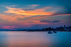 Eine ruhige Wasserstadt im Abenddämmerung, mit Booten auf dem Wasser und einer entfernten Skyline.