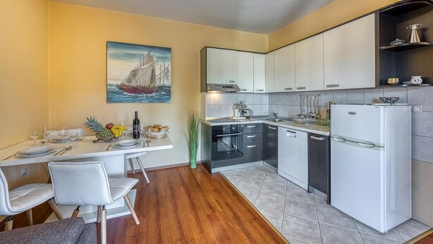 A compact kitchen with white cabinets, a built-in oven, and a refrigerator. - Coastal Paradise Villa With Pool (Sveti Filip i Jakov)