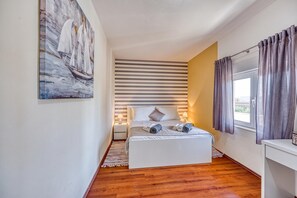 Ein Hotelzimmer mit Bett, Nachttischen, einem Fenster mit Vorhängen, einem Bild an der Wand und einem gestreiften Wanddesign.