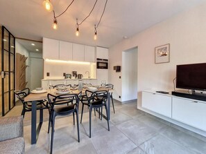 A modern kitchen with white cabinets, a dining table with chairs, and a flat-screen TV on a white cabinet. - 200m from resort center, 1st floor, balcony, tv, ski locker, 40m², Saint Martin de Belleville (Saint-Martin-de-Belleville)