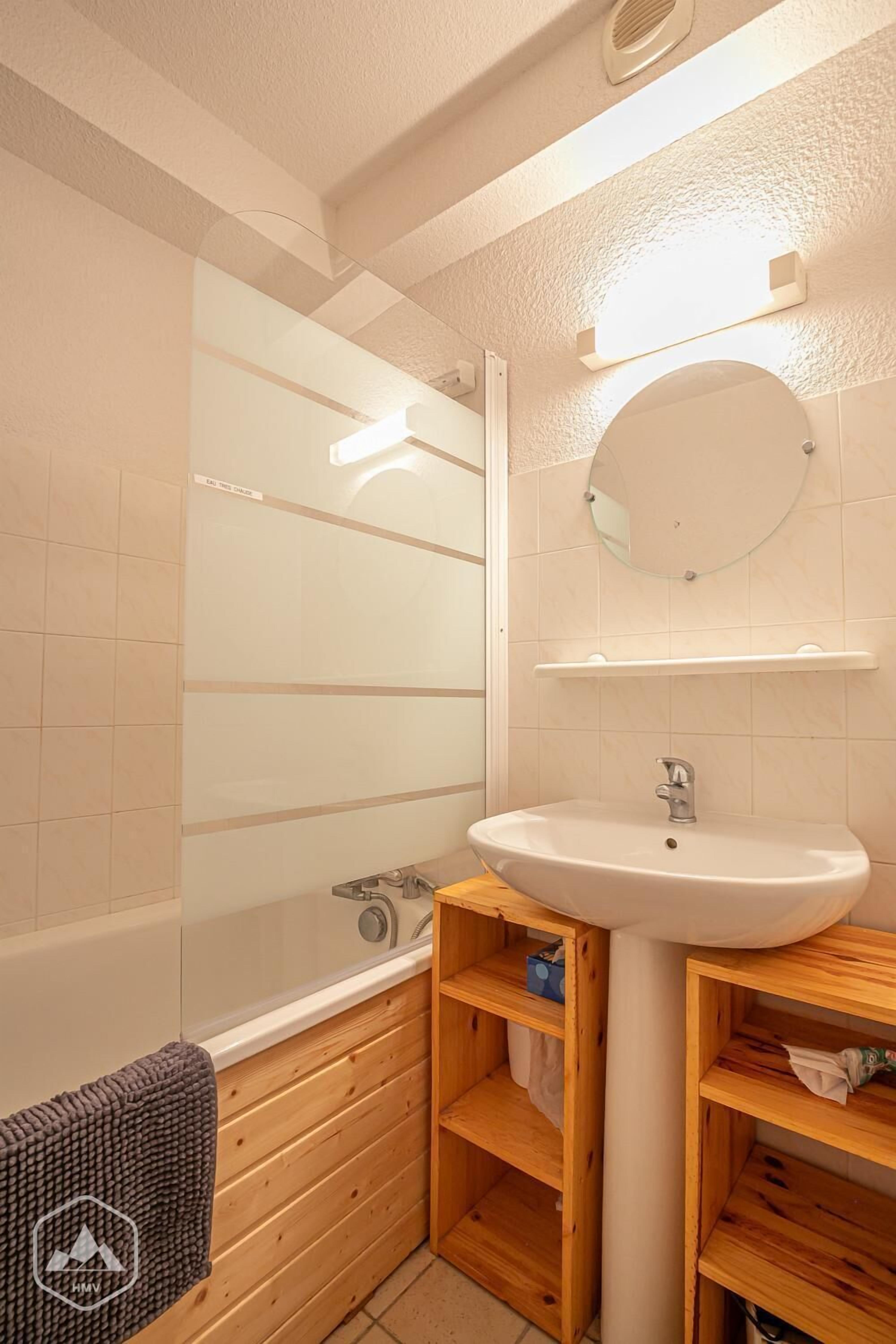 Un baño con un lavabo blanco, un espejo y un mueble de tocador de madera.