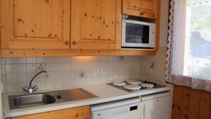 Uma cozinha compacta com armários de madeira, micro-ondas, pia e lava-louças.