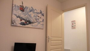 Quarto com televisão na parede, uma porta e um cartaz.