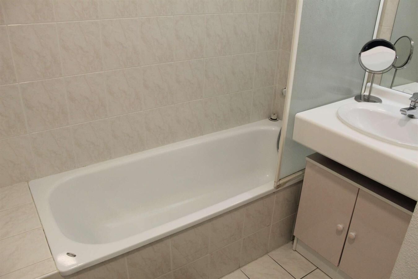 A bathroom with a bathtub, a sink, and a mirror.