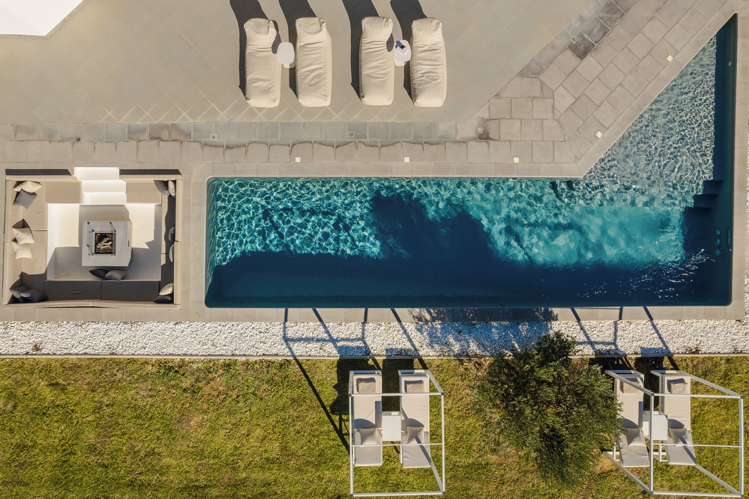 An aerial view of a modern outdoor pool area with lounge chairs and a seating area.
