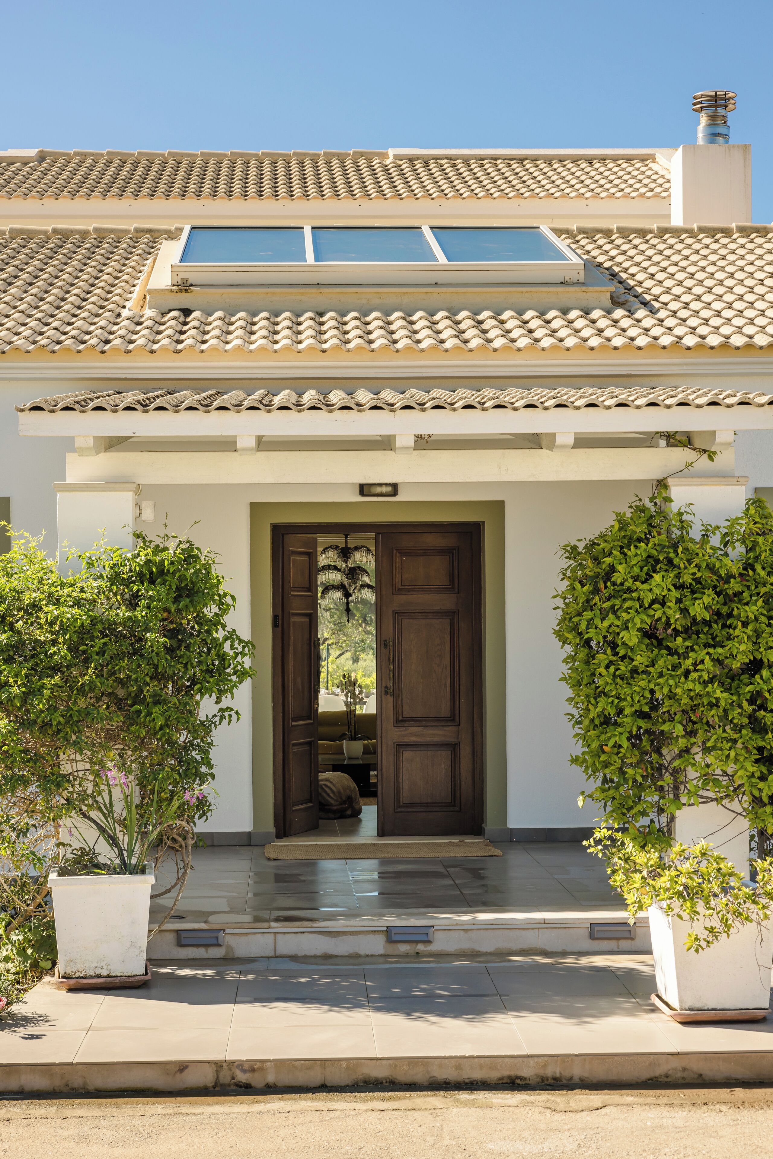 A house with a tiled roof, a wooden door, and potted plants.