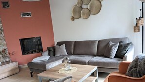 A modern living room with a grey sofa, orange armchairs, a wooden coffee table, and a fireplace. - Traumhafte Wohnung Über Zwei Ebenen mit Infrarotkabine, Balkon und Terrasse (Göhren-Lebbin)