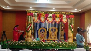 A stage with a floral backdrop and a seated audience. - Hotel Woodside Prestige Tirupati (Tirupati)