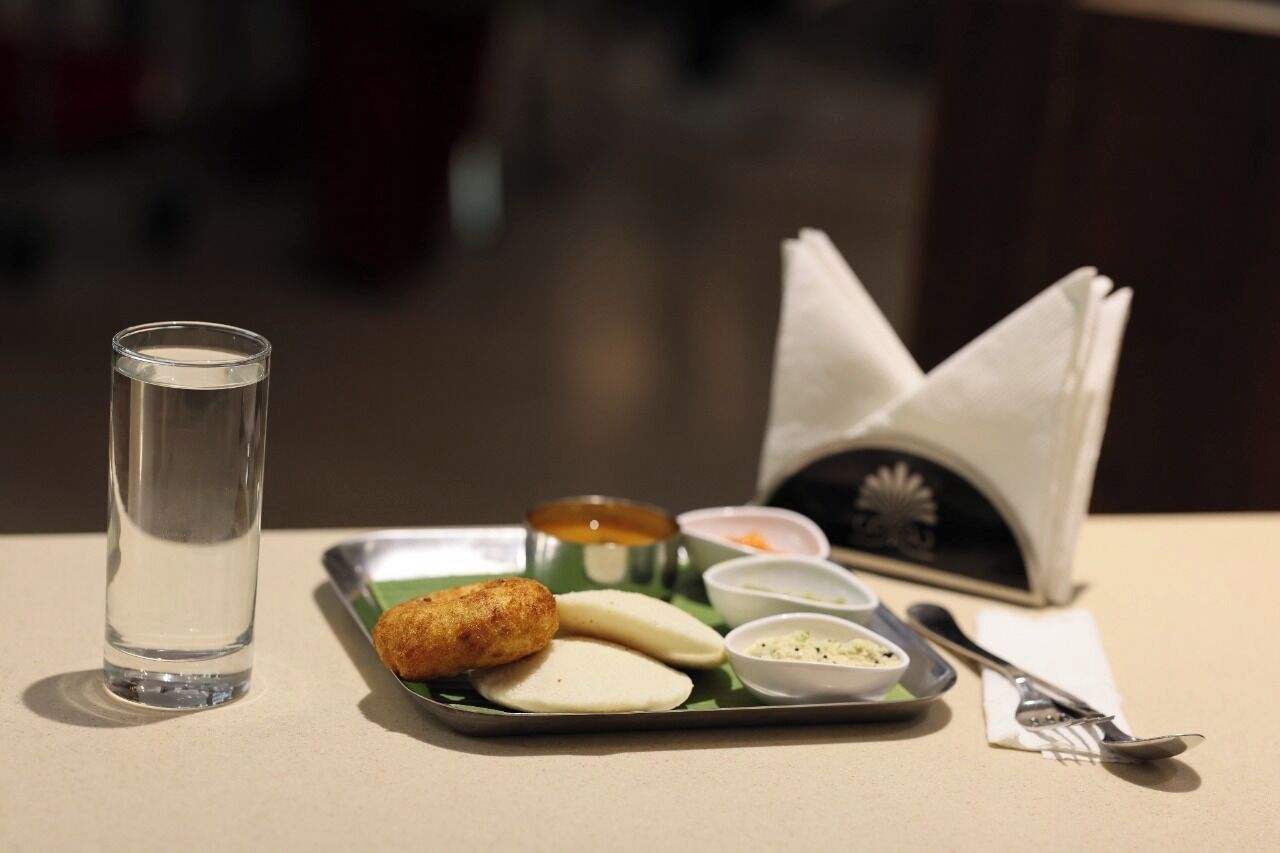 Una bandeja con comida, un vaso de agua y una servilleta sobre una mesa.