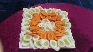 A square plate with sliced vegetables arranged in a heart pattern.