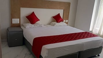 A neatly made bed with a red accent, a wooden headboard, and a bedside table.