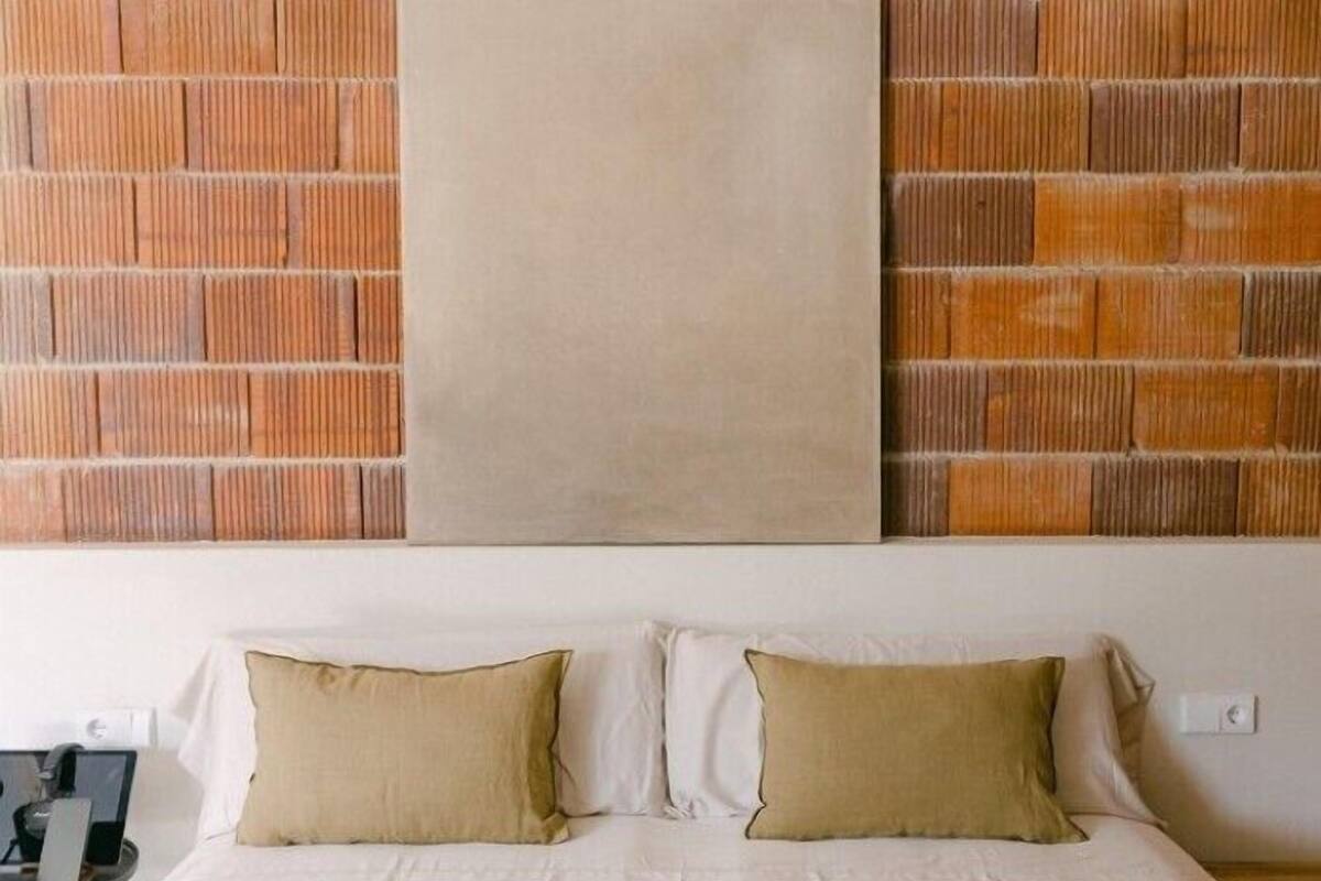 Un dormitorio con una cama, dos almohadas y una pared con diseño de ladrillo.