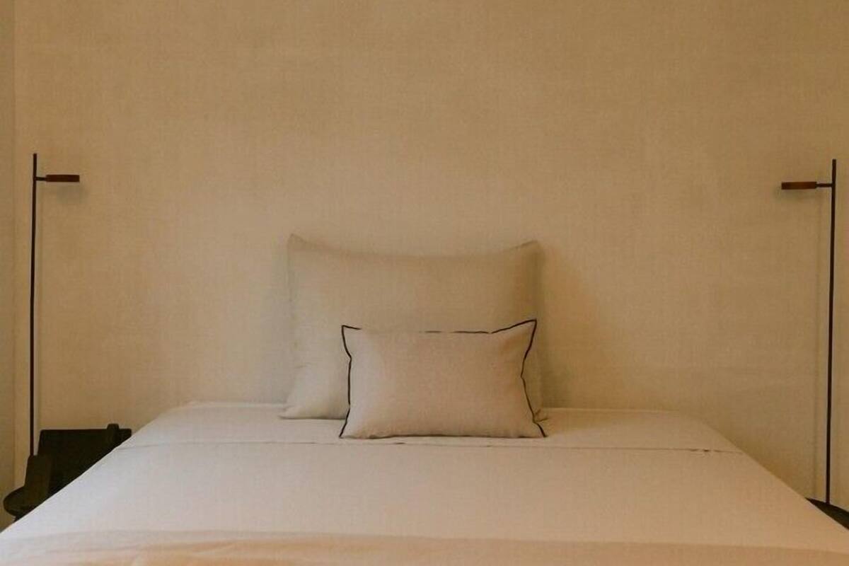 Una cama con dos almohadas y una pared lisa.