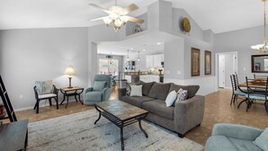 A spacious living room with a large sofa, a coffee table, and a dining area. - Paradise Reef Private Pool! Walk to the Beach! Sleeps 10! Jacuzzi! Pet Friendly! (Miramar Beach)