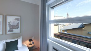 A hotel room with a bed, a bedside table with a lamp, a water bottle, and two framed artworks on the wall. - Sweett | Classy Duomo II (Milano)