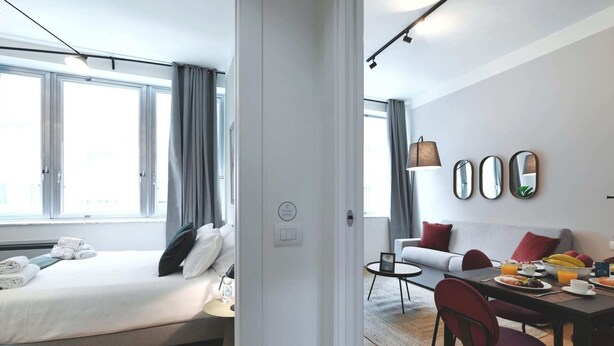 Et moderne hotelværelse med en seng, et lille bord med morgenmad, en sofa og et spiseområde.