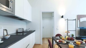 Et moderne køkken med mikroovn, brødrister og vask. Et spisebord er dækket med morgenmadsprodukter.