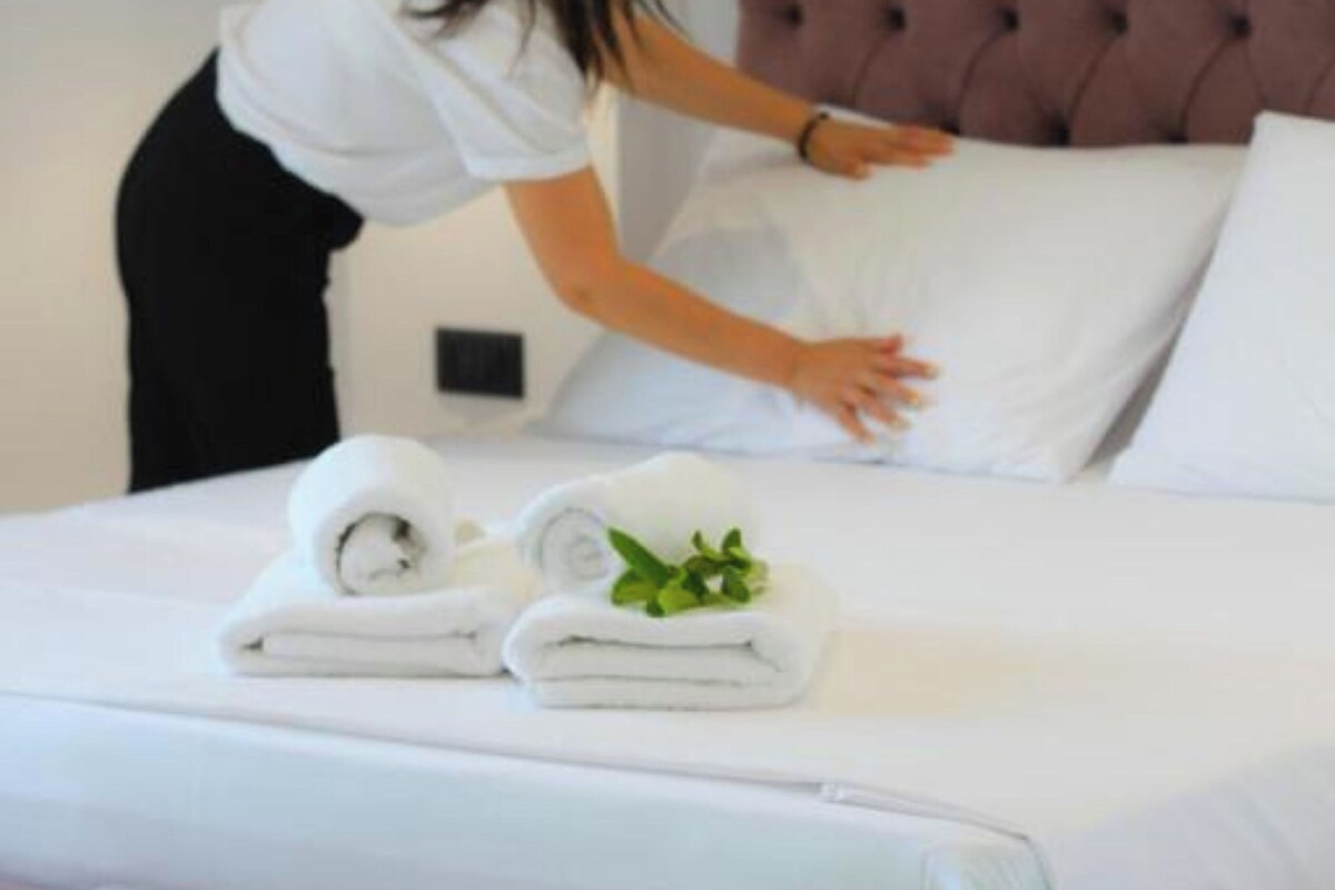 A person arranging pillows on a bed in a hotel room.