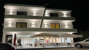 A multi-story hotel with outdoor seating and umbrellas. - Vila Mia (Sarandë)