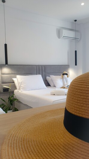 A modern bedroom with a bed, bedside tables, a potted plant, and an air conditioning unit. - Vila Mia (Sarandë)