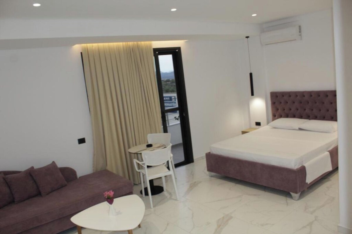 A modern hotel room with a bed, a sofa, a small table, and a chair.