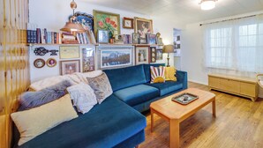 Un salon chaleureux avec un canapé bleu, une table basse en bois et une bibliothèque remplie de livres et de photos encadrées.