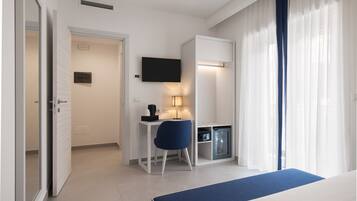 Une chambre d’hôtel comprenant un lit, un bureau avec une chaise, une télévision et un minibar.