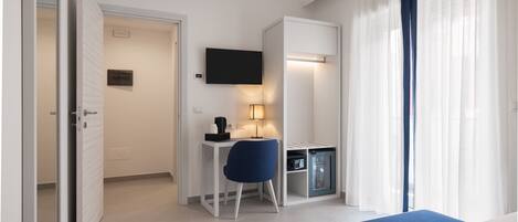 Une chambre d’hôtel comprenant un lit, un bureau avec une chaise, une télévision et un minibar.