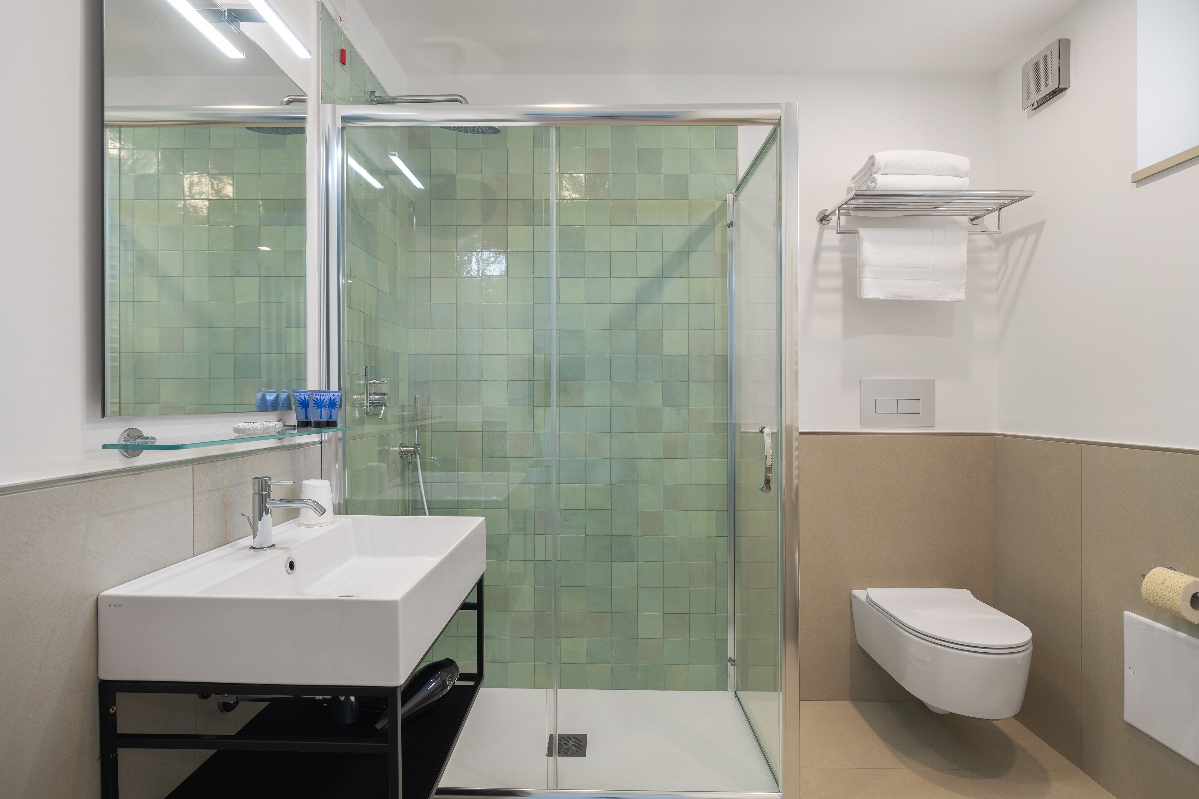 Et moderne badeværelse med et glasvægshus, en hvid vask og et toilet.