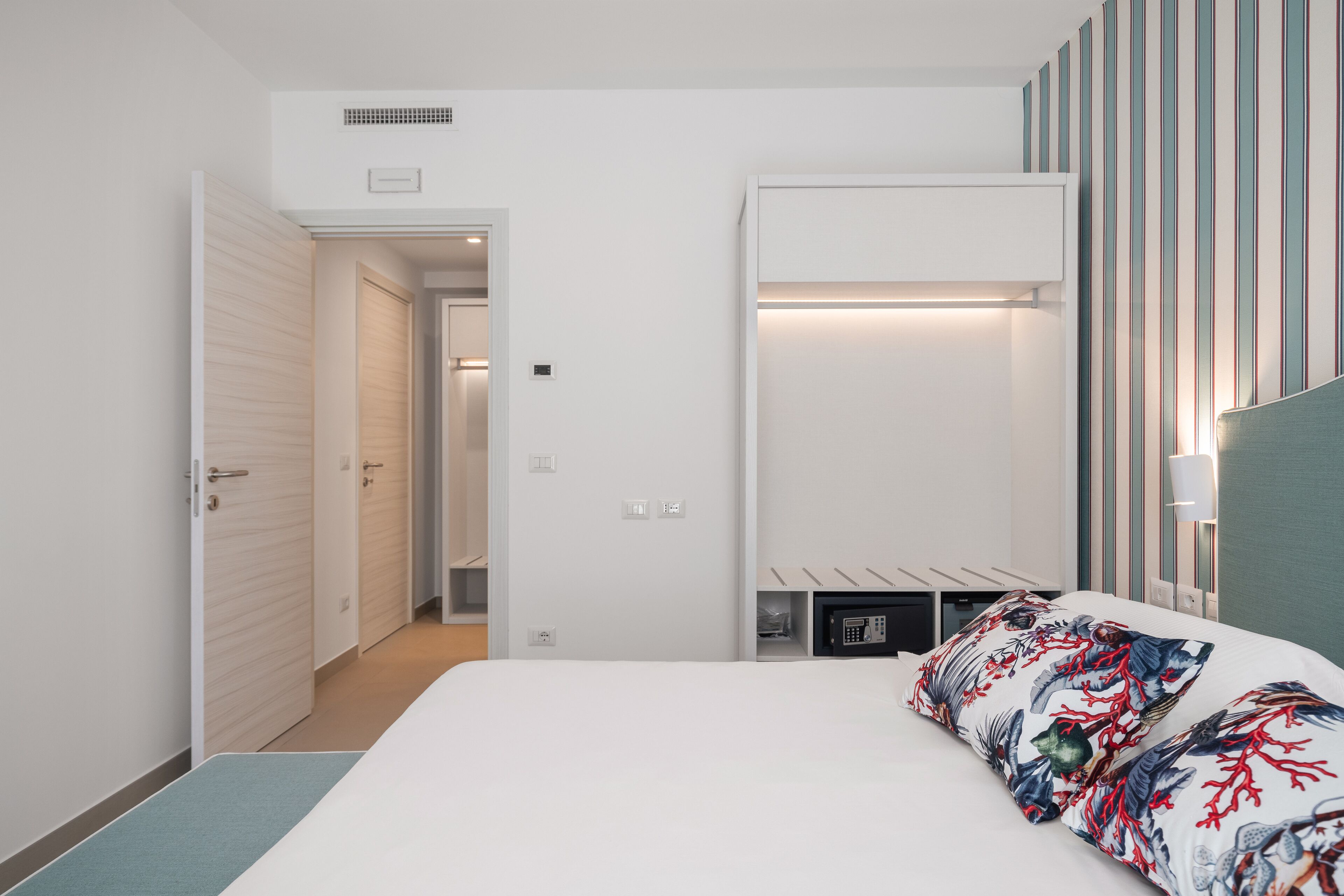 Een moderne hotelkamer met een groot bed, een nachtkastje, een garderobe en een gestreept muur.