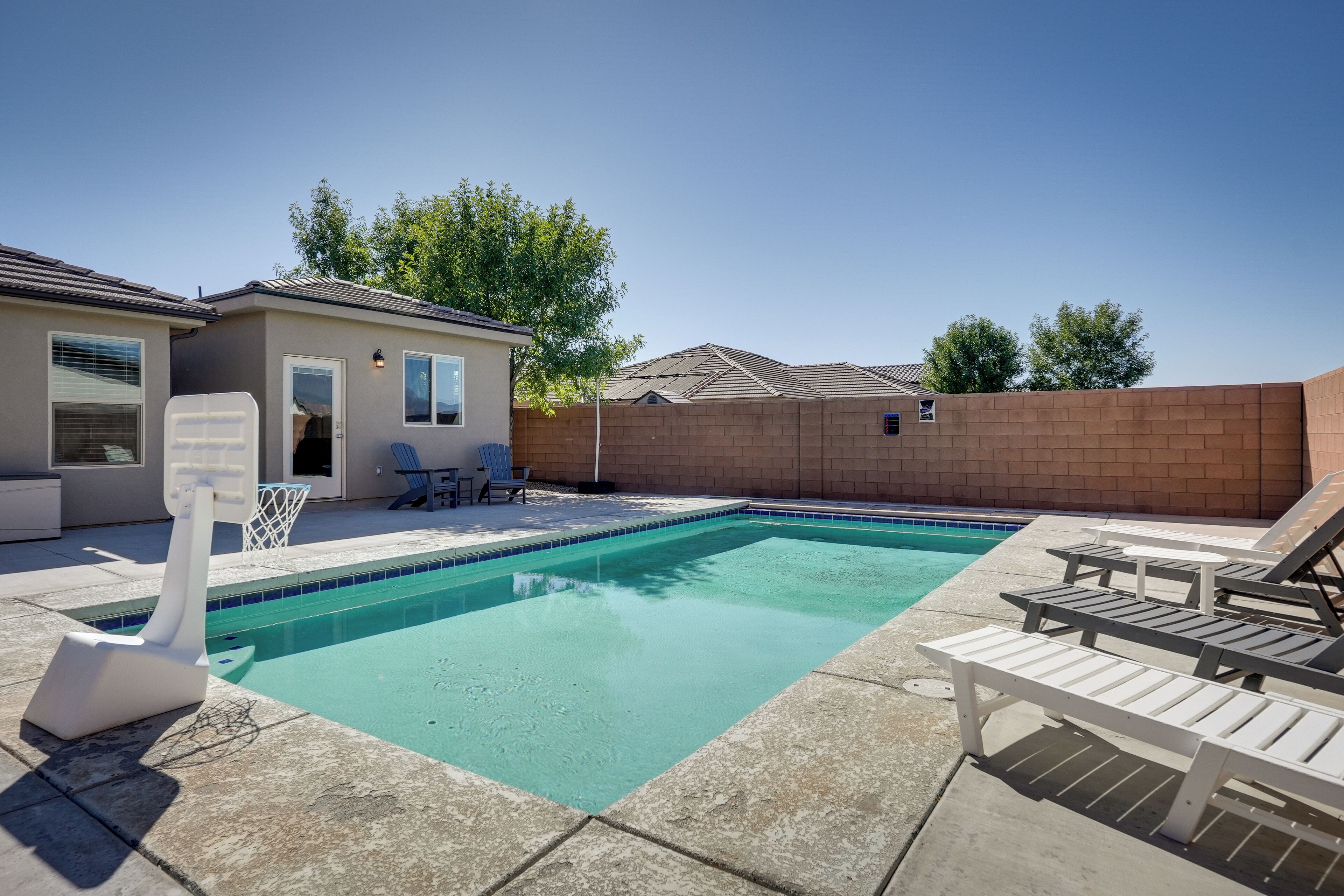 A swimming pool with lounge chairs and a small building with a door and windows.