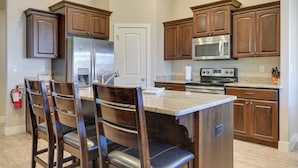 Una cocina con armarios de madera, electrodomésticos de acero inoxidable y encimera de mármol.