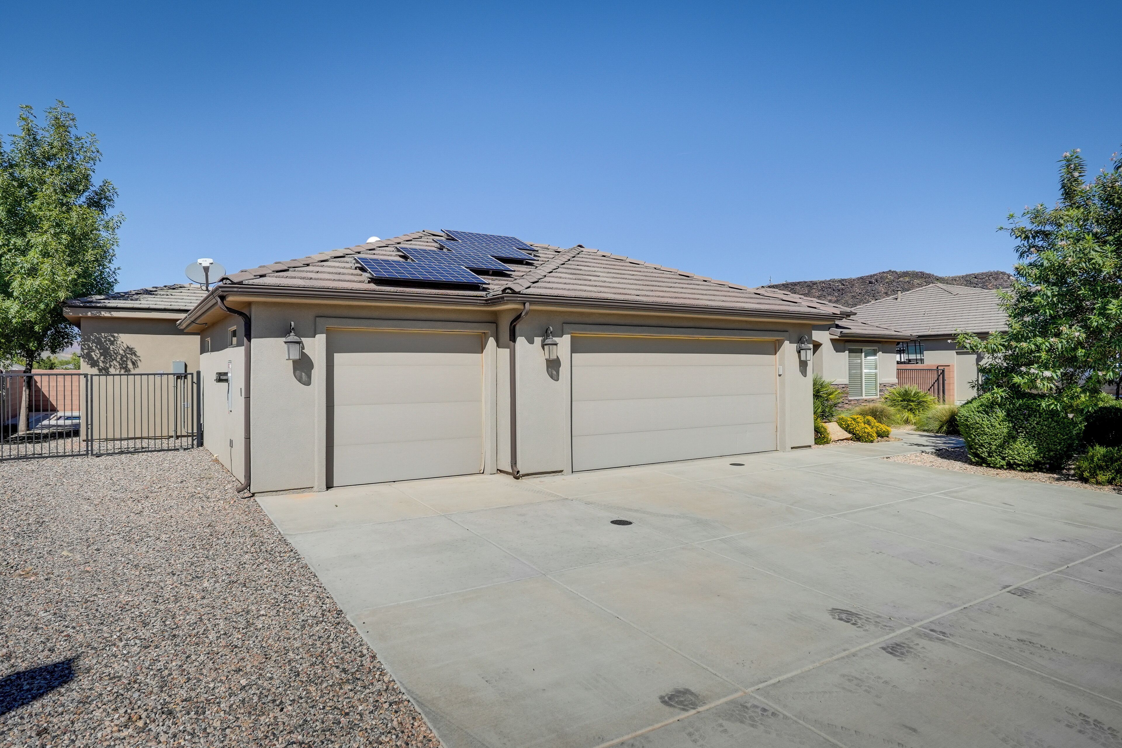 A single-story house with a garage, solar panels on the roof, and a clear driveway.