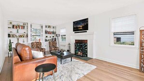A living room with a fireplace, bookshelves, a sofa, a coffee table, and a television.