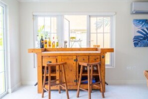 A kitchen with a wooden island, bar stools, and a view of the outside through large windows.