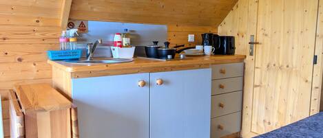 A compact kitchen with wooden cabinets, a sink, and a countertop.