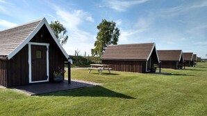 Eine Reihe von rustikalen Holzhäusern mit Satteldächern, ein Picknicktisch und eine Wiese.