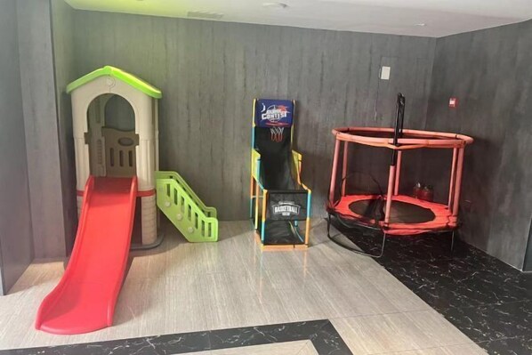 Et legeområde for børn med en rød rutsjebane, et lille klatrestativ og en trampolin.